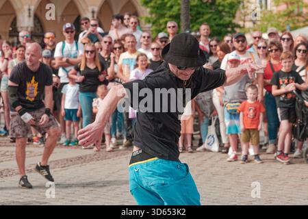 Der Straßenkünstler von Kraków B-Boys Familia zeigt während einer Breakdance-Show Hip-Hop-Fußarbeit, wobei die Zuschauer genau zuschauen. Stockfoto