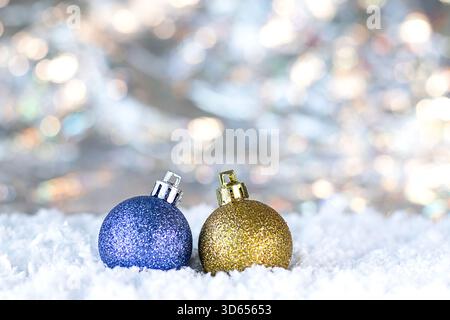 Glitzernde blau-goldene Weihnachtsdekorationen im Schnee mit sanftem Bokeh-Hintergrund Stockfoto