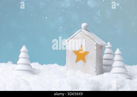 Charmantes handgefertigtes Ornament mit rustikaler Hütte und Miniatur-Kiefern im Winter Stockfoto