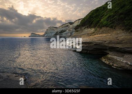Küstenklippen und ruhiges Meer unter einem sanft beleuchteten Himmel bei Sonnenuntergang, die einen friedlichen und malerischen Blick auf die Küste bieten. Stockfoto
