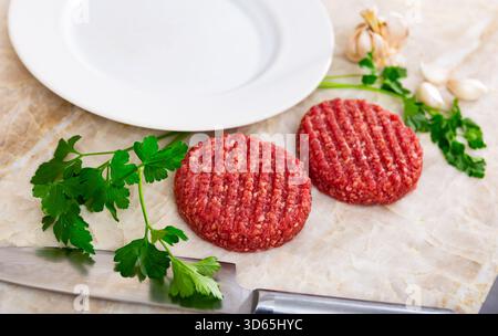Rohe Rinderpasteten für Burger mit Gemüse und Knoblauch Stockfoto