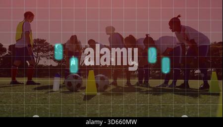 Training Team und Coach dehnen sich bei Sonnenuntergang auf einem grasbewachsenen Platz mit Bällen, Kegeln, gelbem Lätzchen und Gitter Stockfoto
