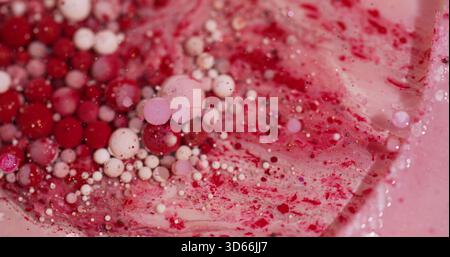 Ölblasen. Lackflüssigkeit. Defokussierte rote rosa weiße bunte funkelnde Glitzerpartikel fließen schweben auf abstraktem Bokeh-Kunsthintergrund. Stockfoto