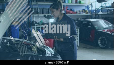 Ich überprüfe die Technikerin, die Motordaten mit einem Laptop in der Garage ansieht, und trage HUD-Overlays in Navy-Overall Stockfoto