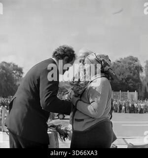 Slawjansk, Ukraine, UdSSR - 8. September 1985: Emotionales Archivfoto einer Preisverleihung während des Stadttags. Ein Beamter im Anzug schenkt einem älteren Ehepaar, das auf der Bühne steht, respektvoll Blumen. Die Frau trägt ein traditionelles Kopftuch. Dieses Schwarzweiß-Bild spiegelt die tiefe sowjetische Tradition wider, Arbeitsveteranen oder angesehene Bürger vor einer großen Menschenmenge in der Donezker Region öffentlich zu ehren und die sozialen Werte der friedlichen Ära wiederzugeben. Stockfoto