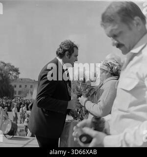 Slawjansk, Ukraine, UdSSR - 8. September 1985: Emotionales Archivfoto einer Preisverleihung während des Stadttags. Ein Beamter im Anzug schenkt einem älteren Ehepaar, das auf der Bühne steht, respektvoll Blumen. Die Frau trägt ein traditionelles Kopftuch. Dieses Schwarzweiß-Bild spiegelt die tiefe sowjetische Tradition wider, Arbeitsveteranen oder angesehene Bürger vor einer großen Menschenmenge in der Donezker Region öffentlich zu ehren und die sozialen Werte der friedlichen Ära wiederzugeben. Stockfoto