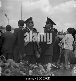 Slawjansk, Ukraine, UdSSR - 8. September 1985: Archivfoto zweier Offiziere in Uniform, die sich während des Stadtfestes unterhalten. Der Mann auf der linken Seite trägt einen zeremoniellen Schärpe mit der Aufschrift 'Ehrenbürger von Slawjansk' und hält Blumen. Sie stehen in der Nähe eines mit Nelken bedeckten Monuments. Dieses Schwarzweiß-Bild fängt einen Moment der Kommunikation zwischen den angesehenen Gästen und die Atmosphäre des Respekts in der Region Donezk während der friedlichen Sowjetzeit ein. Stockfoto