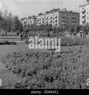Slawjansk, Ukraine, UdSSR - 8. September 1985: Malerischer Blick vom zentralen Platz in Richtung Lenin-Straße (heute Shevchenko-Straße). Das Schwarzweiß-Foto zeigt ein großes Blumenbeet im Vordergrund und die Bürger, die während des City Day-Festes durch die Gassen des Parks schlendern. Im Hintergrund stehen typische sowjetische fünfstöckige Wohnhäuser. Dieses Bild spiegelt die Stadtplanung, die Grünzonen und die friedliche Atmosphäre der Region Donezk in den 1980er Jahren wider Stockfoto