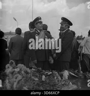 Slawjansk, Ukraine, UdSSR - 8. September 1985: Archivfoto zweier Offiziere in Uniform, die sich während des Stadtfestes unterhalten. Der Mann auf der linken Seite trägt einen zeremoniellen Schärpe mit der Aufschrift 'Ehrenbürger von Slawjansk' und hält Blumen. Sie stehen in der Nähe eines mit Nelken bedeckten Monuments. Dieses Schwarzweiß-Bild fängt einen Moment der Kommunikation zwischen den angesehenen Gästen und die Atmosphäre des Respekts in der Region Donezk während der friedlichen Sowjetzeit ein. Stockfoto