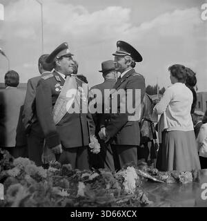 Slawjansk, Ukraine, UdSSR - 8. September 1985: Archivfoto zweier Offiziere in Uniform, die sich während des Stadtfestes unterhalten. Der Mann auf der linken Seite trägt einen zeremoniellen Schärpe mit der Aufschrift 'Ehrenbürger von Slawjansk' und hält Blumen. Sie stehen in der Nähe eines mit Nelken bedeckten Monuments. Dieses Schwarzweiß-Bild fängt einen Moment der Kommunikation zwischen den angesehenen Gästen und die Atmosphäre des Respekts in der Region Donezk während der friedlichen Sowjetzeit ein. Stockfoto