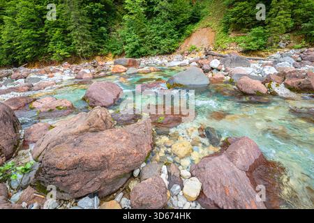Rote Felsen im türkisfarbenen Wasser des Flusses Slizza bei Tarvisio in den Julischen Alpen, Italien Stockfoto