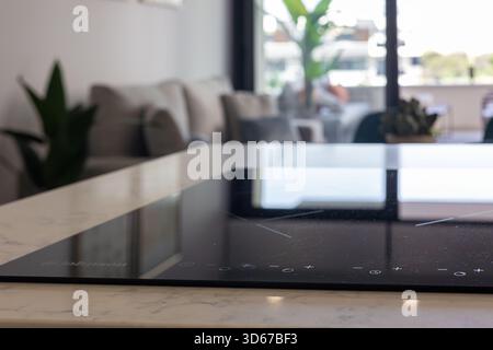 Elegante Induktionskochplatte mit Touch-Bedienelementen auf der Arbeitsfläche aus weißem Marmor im modernen Innenraum Stockfoto