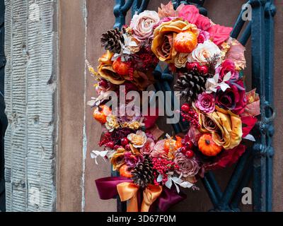Ein orange-roter Herbstkranz aus getrockneten Blumen und Früchten hängt an der Tür Stockfoto