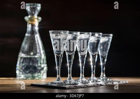 Selektive Fokussierung von fünf Gläsern kalten Wodkas auf Holztisch, Nahaufnahme Stockfoto