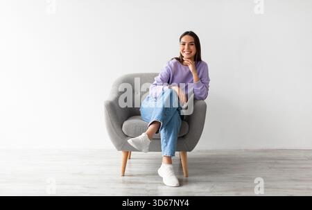 Die ganze Länge einer glücklichen jungen Frau in Freizeitkleidung lächelnd Stockfoto