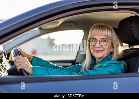 Reife Fahrerin lächelt hinter dem Steuer Stockfoto