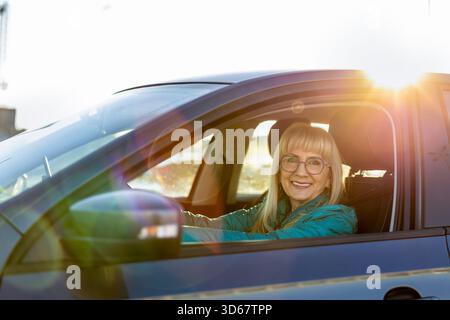 Reife Fahrerin lächelt hinter dem Steuer Stockfoto