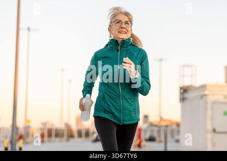 Eine ältere Frau joggt draußen bei Sonnenuntergang Stockfoto