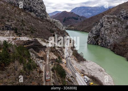 Aus der Vogelperspektive einer Serpentinenstraße und einer Eisenbahnstrecke, die den Fluss Neretva durchquert und durch zerklüftete Berge in der Nähe von Tunneln, Lisičići, Föderation von Bosnien, führt Stockfoto