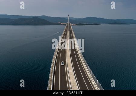 Die Pelješac-Brücke aus der Vogelperspektive erstreckt sich kühn über das tiefblaue Wasser und verbindet ferne Ufer unter einem riesigen Himmel, Komarna, Dubrovnik-Neretva Stockfoto