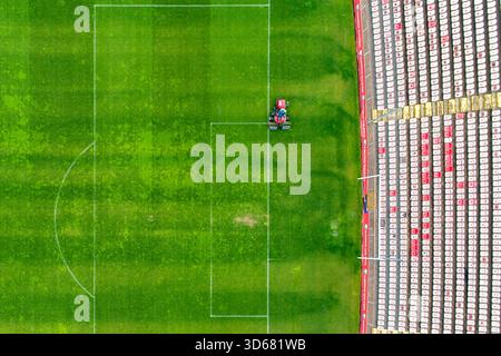 Aus der Vogelperspektive auf ein lebhaftes grünes Fußballfeld, das akribisch neben einem Stadion mit leeren Sitzreihen gemäht wird, Zenica, Federation of Bosniens und He Stockfoto