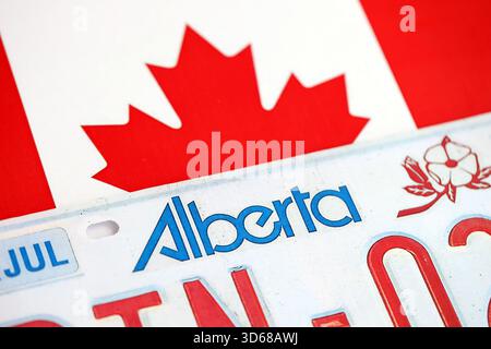 Alberta kanadisches Autokennzeichen auf der Flagge Kanadas Nahaufnahme. Führerschein- und Zulassungskonzept Stockfoto