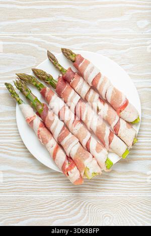 Grüner Spargel in Speckstreifen mit farbigem Pfeffer Stockfoto