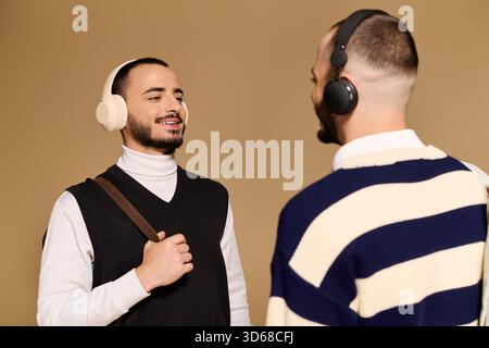 Zwei Brüder teilen sich einen freudigen Moment in trendiger Kleidung, eingetaucht in ihre Musik, während sie lachen. Stockfoto