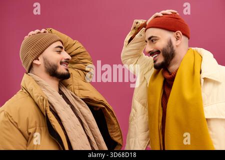 Zwei stilvolle Zwillingsbrüder teilen einen fröhlichen Moment in lebendigen Outfits. Stockfoto
