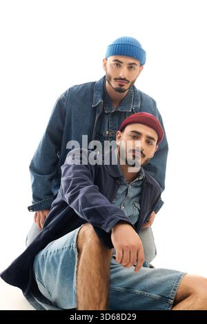 Zwei Brüder in trendiger Kleidung posieren zusammen mit Charme in einem modernen Studio-Raum. Stockfoto