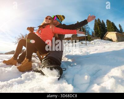 Glückliche Influencer Paar, die Spaß mit Holzrodeln auf schneehohen Bergen haben - Junge Leute genießen Winterurlaub Stockfoto