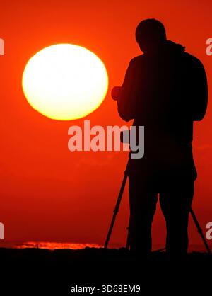 Isle Of Palms, Usa. November 2025. Ein Fotograf im Sonnenlicht fotografiert den Sonnenaufgang am Front Beach am 19. November 2025 in Isle of Palms, South Carolina. Quelle: Richard Ellis/Richard Ellis/Alamy Live News Stockfoto