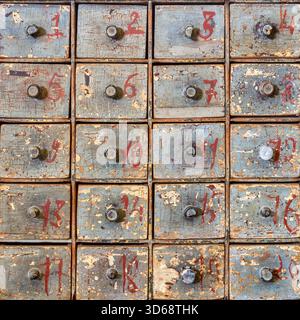 Verwitterter antiker Holzschrank mit 20 nummerierten kleinen Schubladen Stockfoto