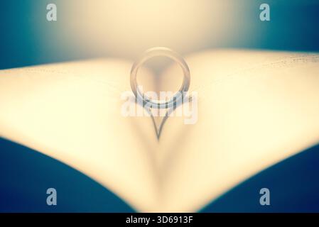 Ehering auf den Seiten eines Buches in Herzform Stockfoto