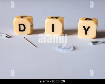 diy Do IT Yourself Nähkonzept mit Nadelschutznadeln und Knopf auf weißem Hintergrund Stockfoto