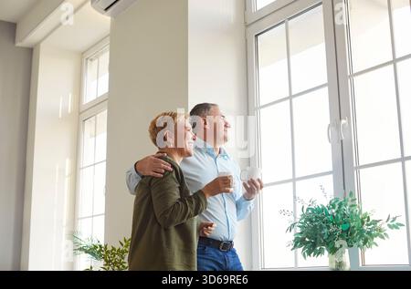 Glückliches Seniorenpaar, reifer Ehemann und Ehefrau, die auf ein neues Fenster blicken Stockfoto