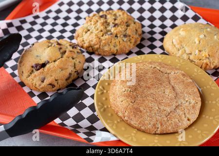 Ein Blick auf mehrere Kekse auf einem Tablett mit Schokoladenchip, Haferflocken-Rosinen, Snickerdoodle und Macadamia-Nuss. Stockfoto