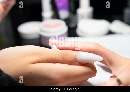 Professionelle Maniküre tragen bei der Nagelverlängerung sorgfältig gellack auf, um eine perfekte, gleichmäßige Abdeckung und Form zu gewährleisten. Stockfoto