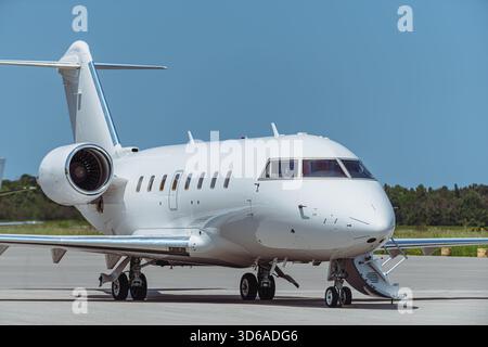 Seitenprofil eines weißen zweimotorigen Business-Jet-Flugzeugs, das auf dem Flughafengelände geparkt ist. Flugzeuge mit Cockpitfenstern, Rumpffenstern, Heckflügeln, Stockfoto