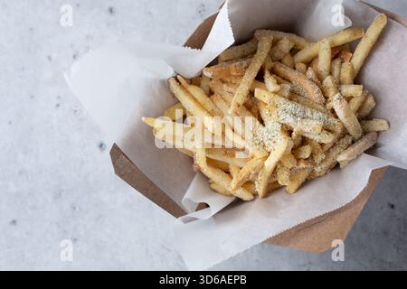 Ein Blick von oben auf einen Karton Pommes frites mit Sauerrahm und Zwiebelpulver. Stockfoto
