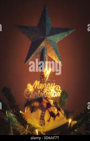 Fröhliche Weihnachtsdekoration mit Glocken und Stern in beleuchtetem weihnachtsbaum Stockfoto