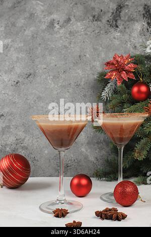 Weihnachtsmartini mit Zimt, Muskatnuss und dunkler Schokolade vor Tannenzweigen, ein Weihnachts- und Weihnachtskonzept. Ein warmes Milchgetränk Stockfoto