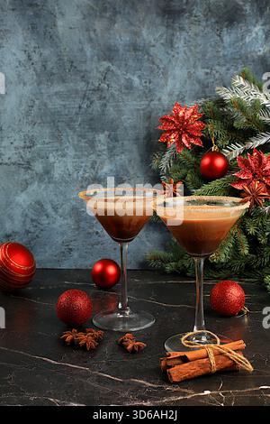 Weihnachtsmartini mit Zimt, Muskatnuss und dunkler Schokolade vor Tannenzweigen, Weihnachts- und Weihnachtskonzept. Ein warmes Milchgetränk du Stockfoto