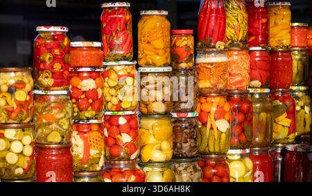Bunte Gläser mit eingelegtem Gemüse, die am Marktstand mit hausgemachten Konserven und verschiedenen Sorten präsentiert werden Stockfoto