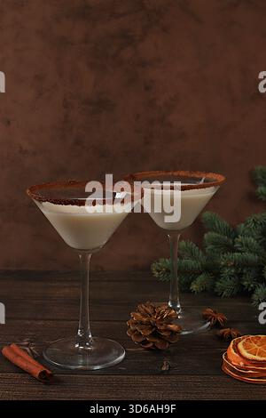 Weihnachtsmartini mit Zimt, Muskatnuss und dunkler Schokolade auf einem Hintergrund mit Tannenzweigen, Konzept für Weihnachten und Winterferien. Milch erwärmen Stockfoto
