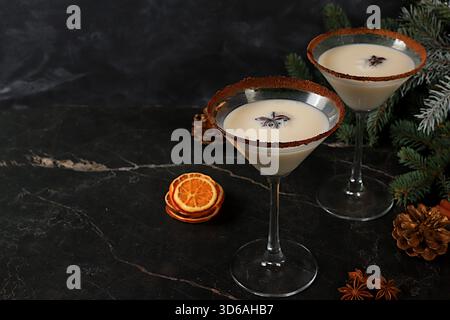 Weihnachtsmartini mit Zimt, Muskatnuss und dunkler Schokolade vor Tannenzweigen, ein Weihnachts- und Weihnachtskonzept. Ein warmes Milchgetränk Stockfoto