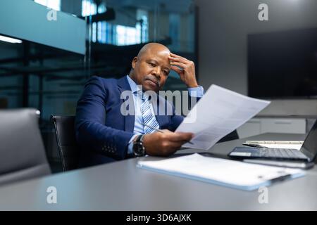 Seriöser reifer afroamerikanischer Geschäftsmann, der Dokumente in modernen Büros analysiert Stockfoto