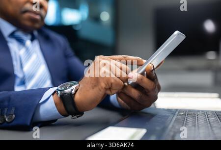 Nahaufnahme eines Reifen schwarzen Geschäftsmannes mit seinem Smartphone am Schreibtisch Stockfoto