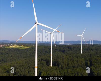 Drei Windräder erheben sich über einem grünen Wald unter klarem Himmel bei Schorndorf, Remstal, Baden-Württemberg Stockfoto