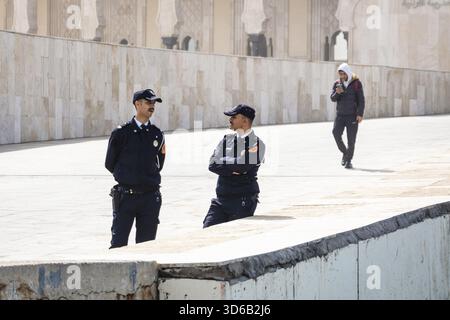 Casablanca, Marokko â€“ 17. April 2025: Zwei uniformierte Polizisten stehen und sprechen im Innenhof der Hassan II Moschee, einer der großen Stockfoto